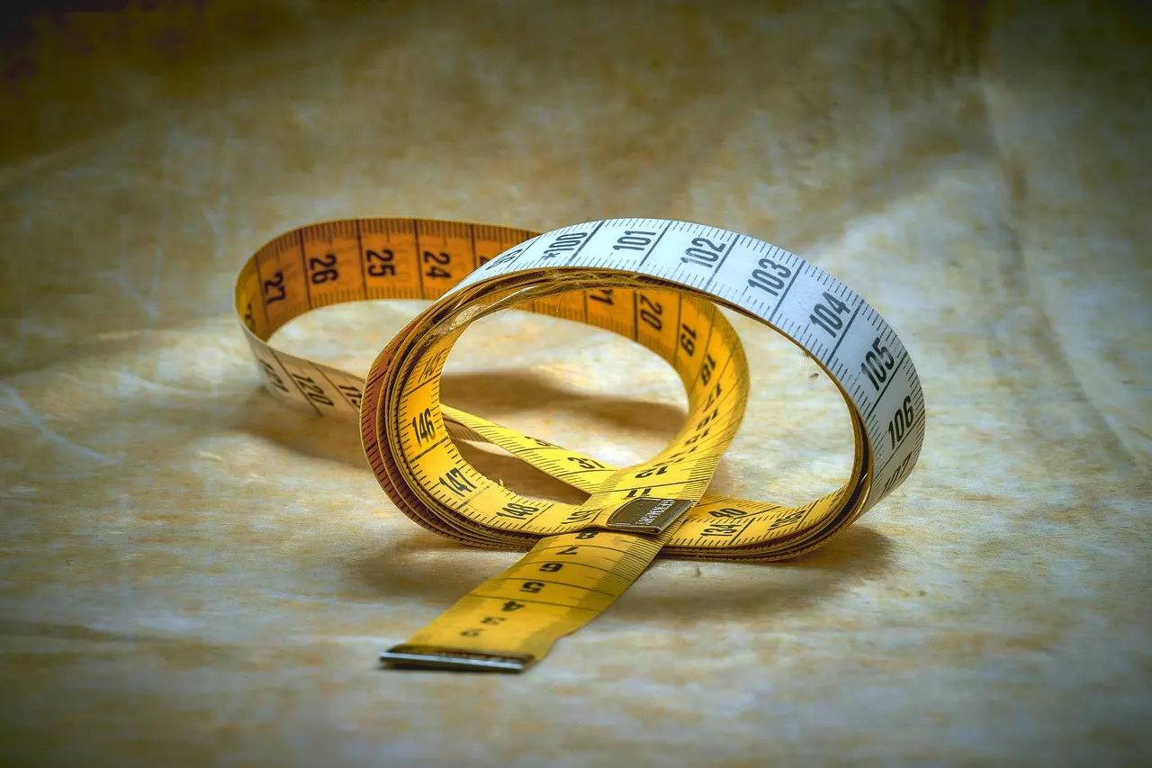 A cloth tailor's tape measure loosely coiled on a wooden table