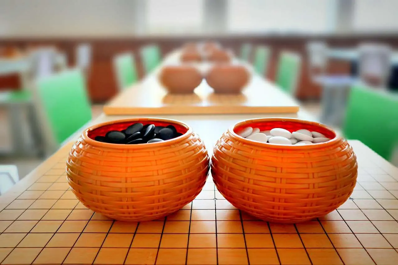 Bowls of black and white Go stones beside a wooden board