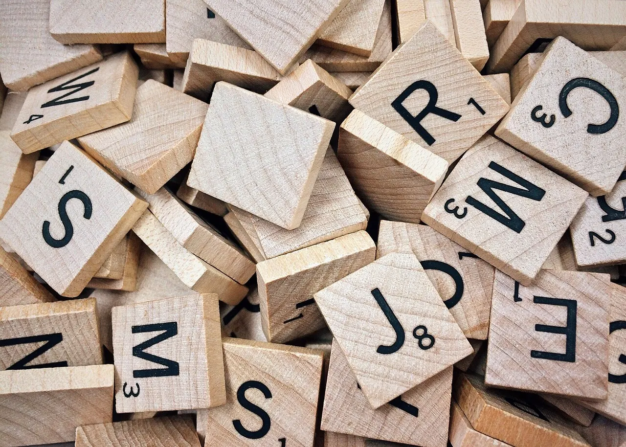 Wooden letter tiles scattered face up on a table, not spelling anything