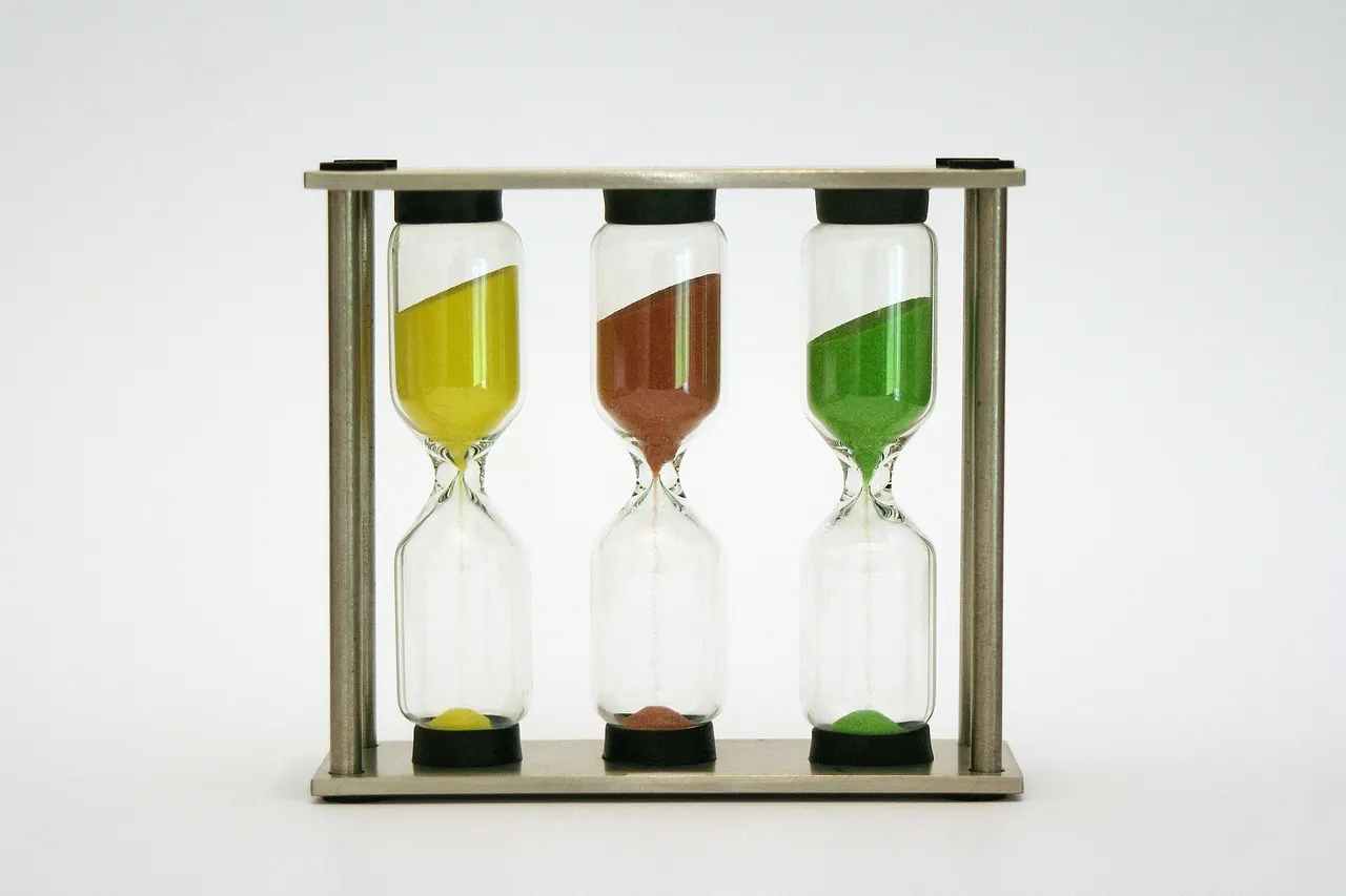 A small glass egg timer with sand running through it