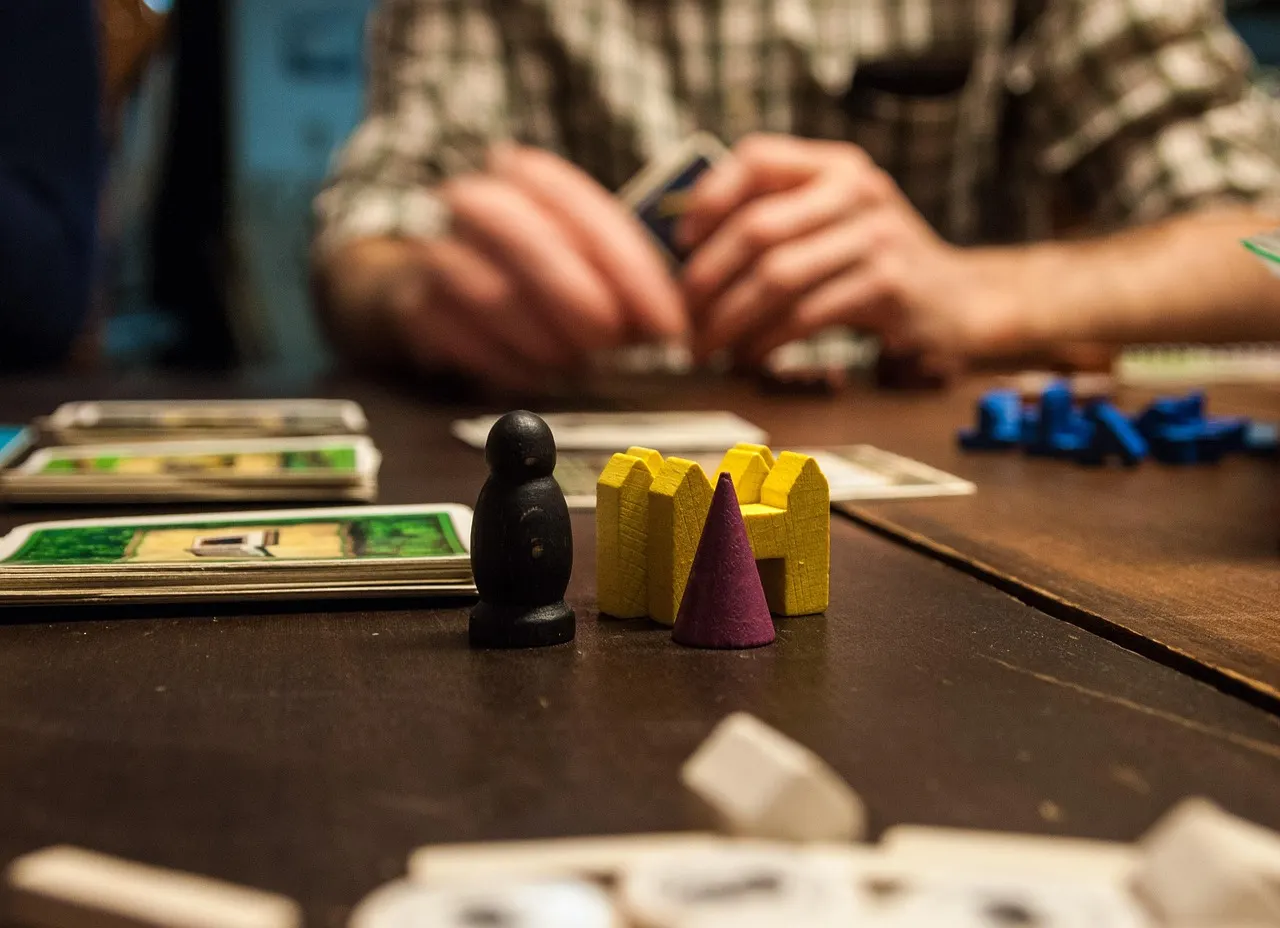 A board game in progress on a wooden table, with dice and playing pieces