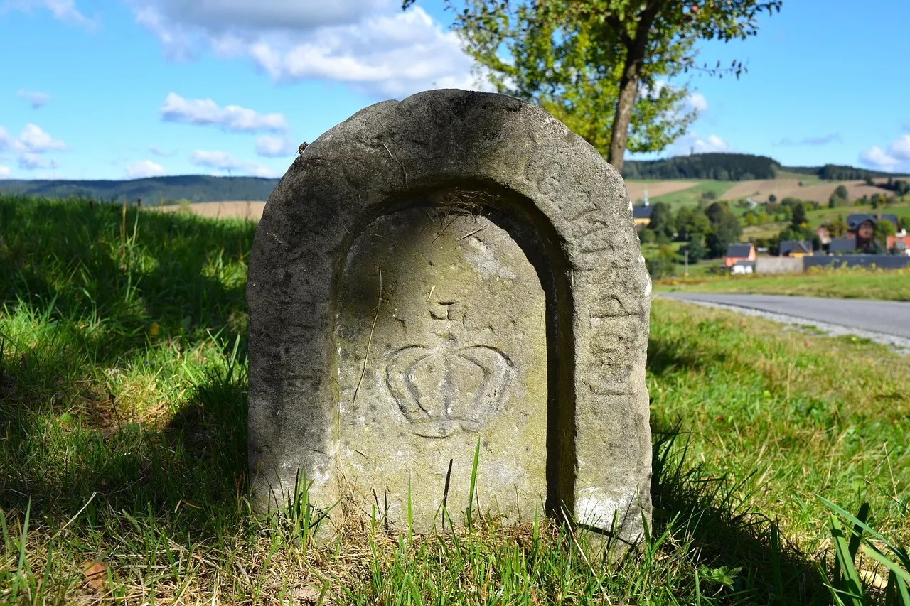 An old carved stone milestone standing in the grass beside a country road