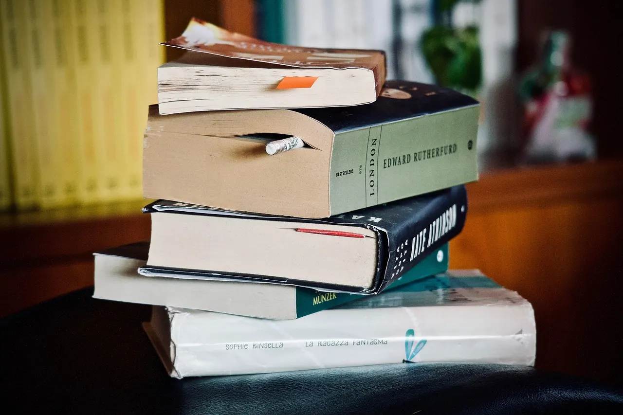 A stack of well-read books with a pencil tucked between the pages