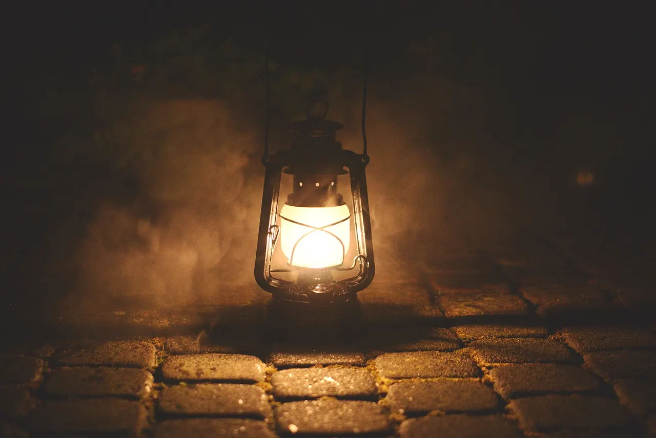 An old oil lamp burning on a stone surface at night