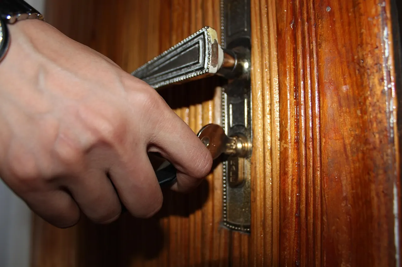 A hand turning a key in the lock of a wooden door